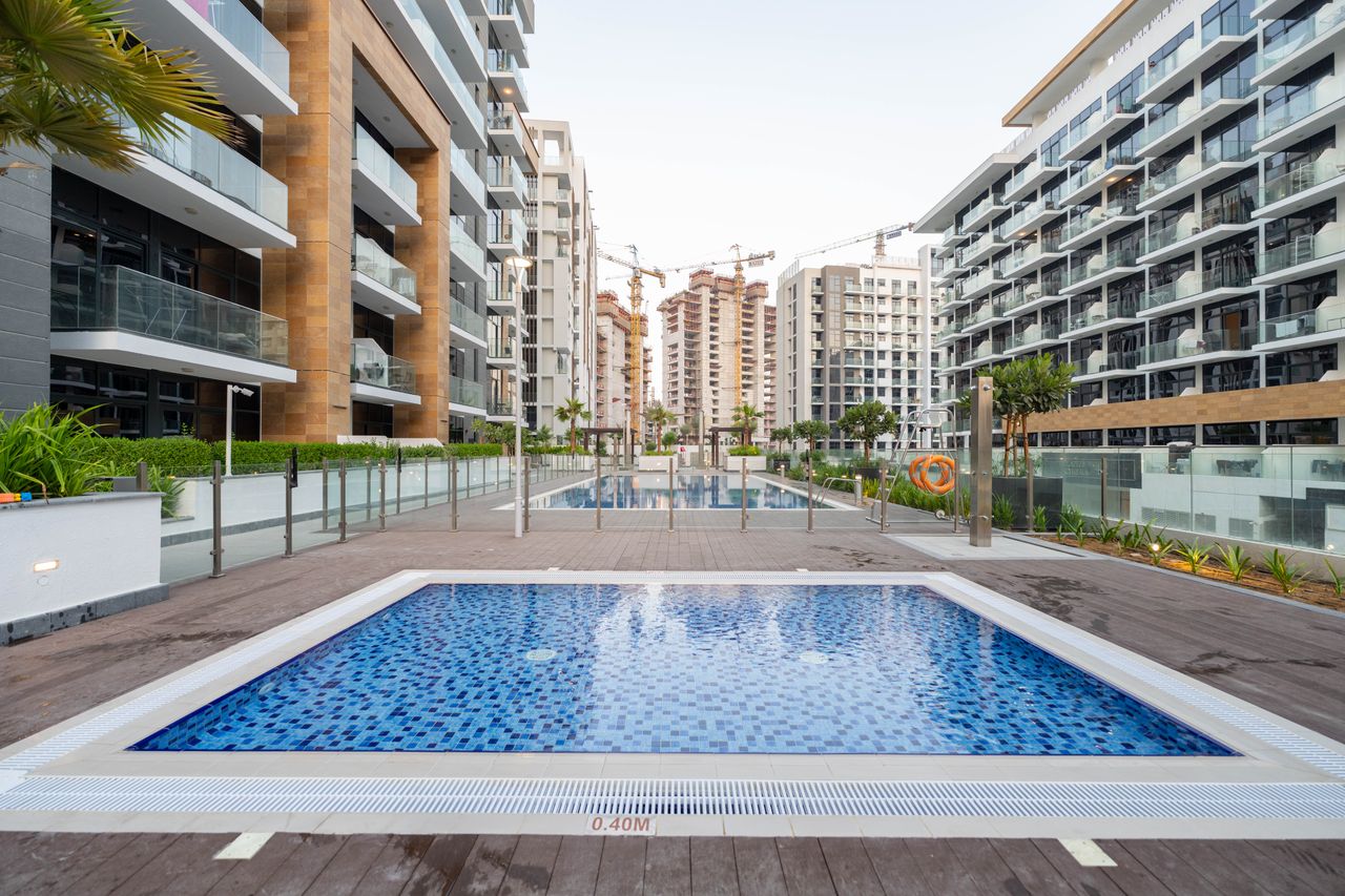Contemporary apartment buildings in Dubai with a swimming pool in the foreground.