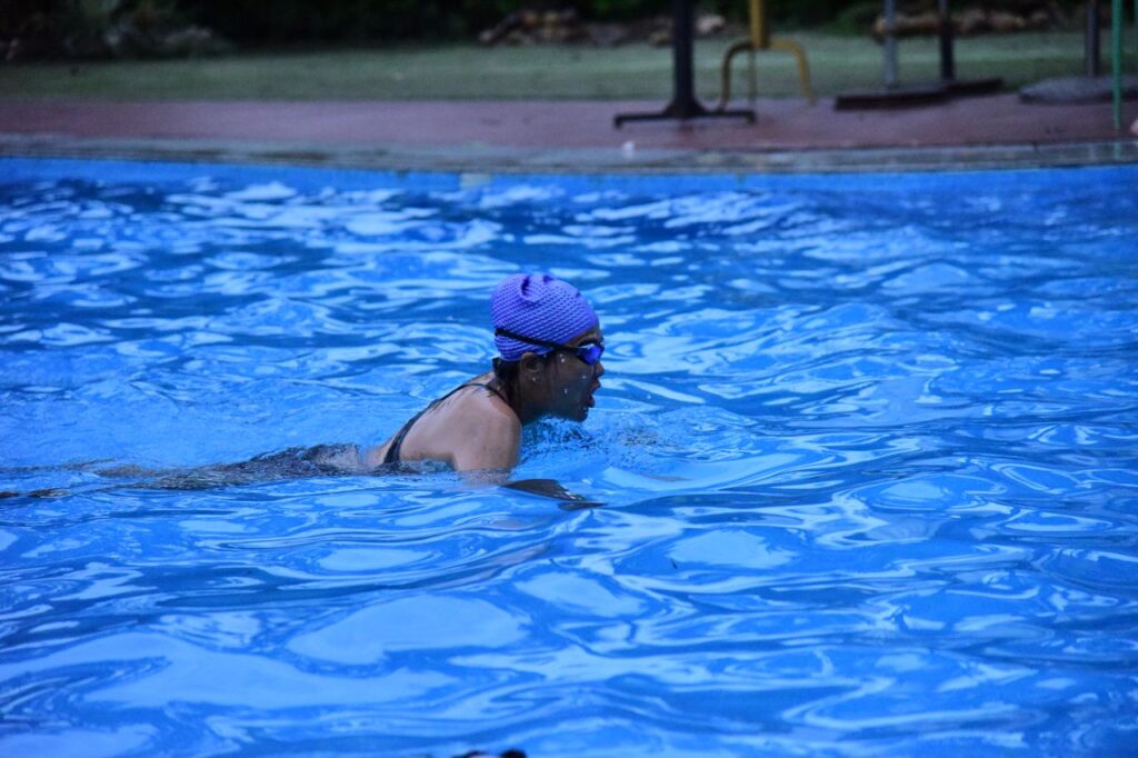 The Art of Drawing Readers In: Your attractive post title goes here An adult woman swimmer practicing strokes in an outdoor pool with a blue swim cap.
